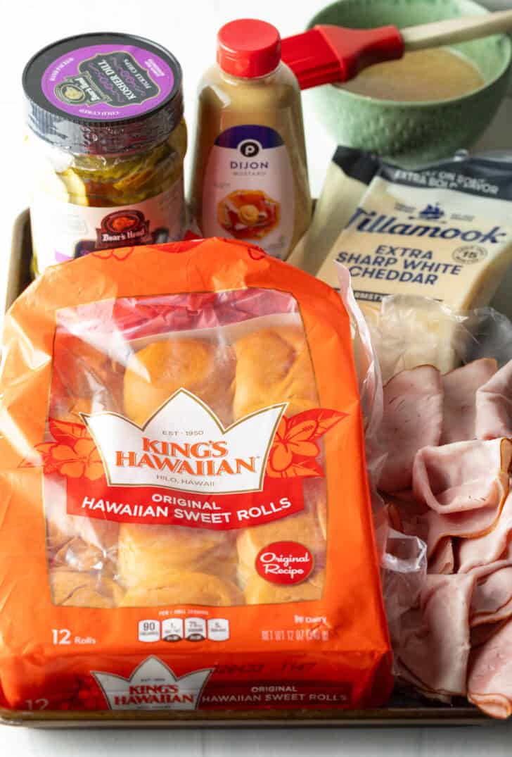 Recipe ingredients: Bag of King's Hawaiian sweet rolls, package of sliced cheese, deli sliced ham, bottle of mustard and jar of pickles.