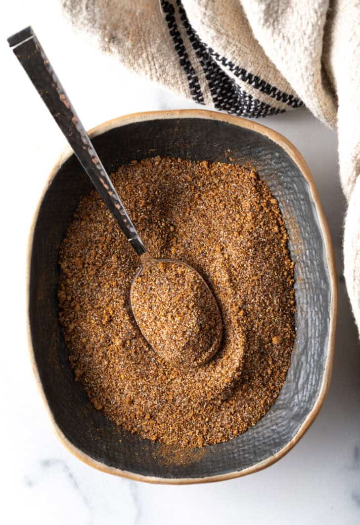 Top down view blend of spices in an oval dish with metal spoon.