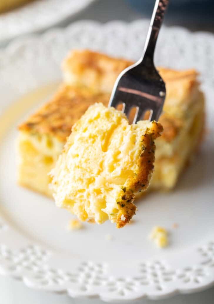 Forkful of egg casserole held to camera.