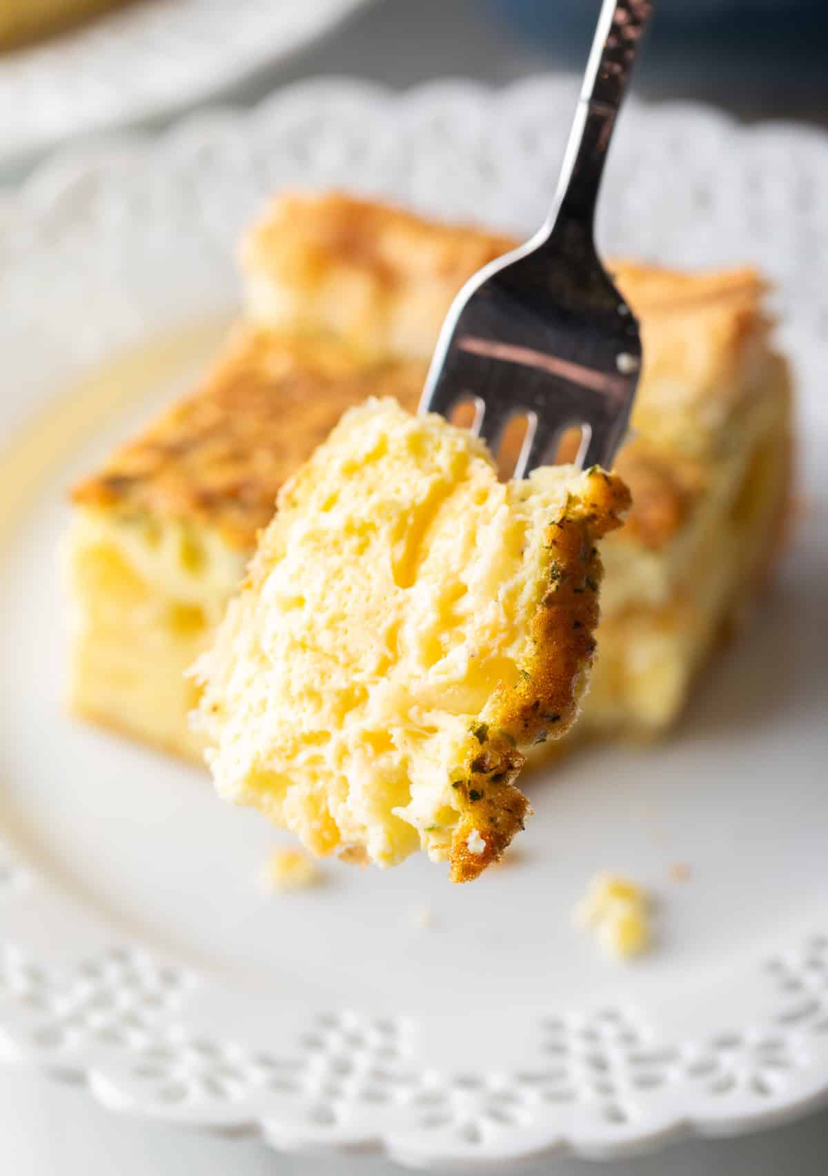 Forkful of egg casserole held to camera.