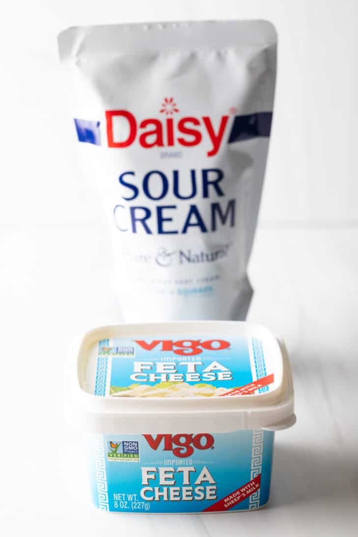 Container of sour cream and square container of feta cheese.
