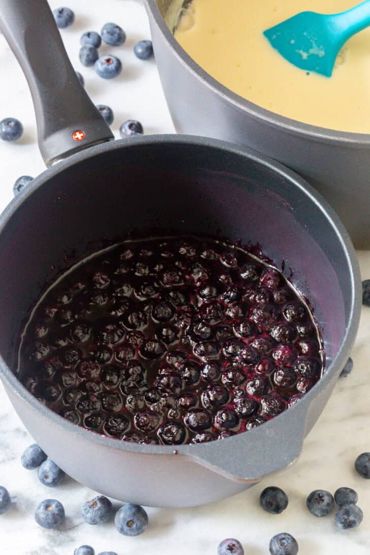 Cooking blueberries in a metal cooking pot.