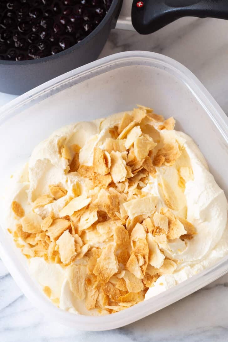 Broken pie crust pieces in a container with vanilla ice cream.
