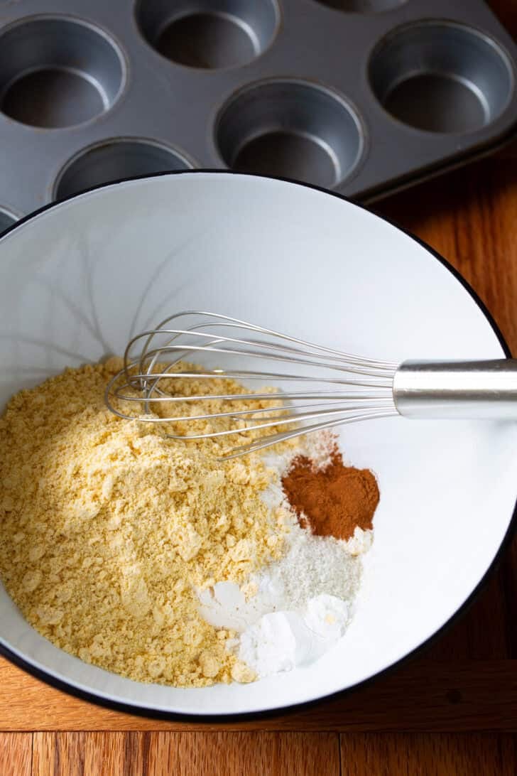 Dry ingredients in a white mixing bowl with whisk.