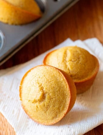Two honey cornbread muffins on a white napkin.
