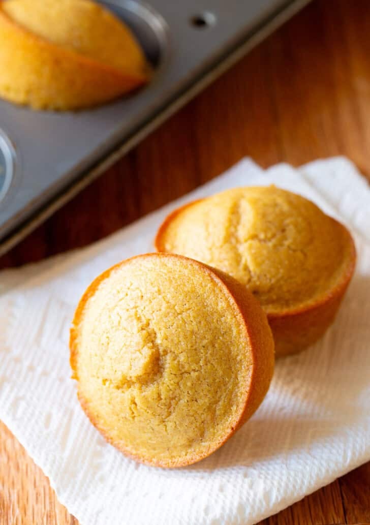 Two honey cornbread muffins on a white napkin.