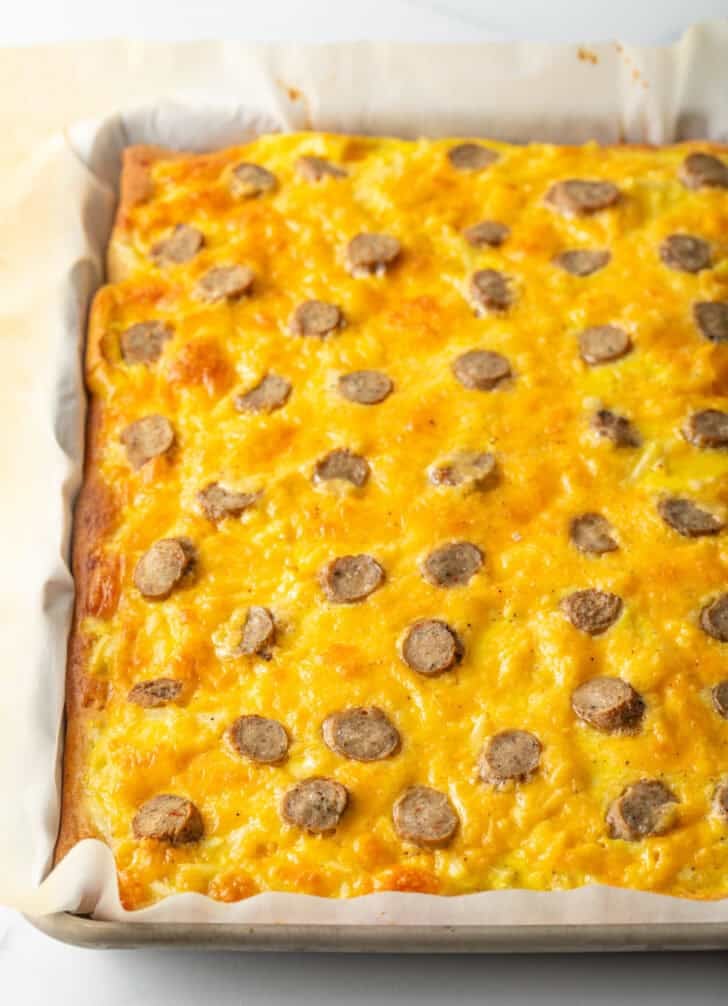 Baked rectangle pizza topped with cheeses and sausage slices.