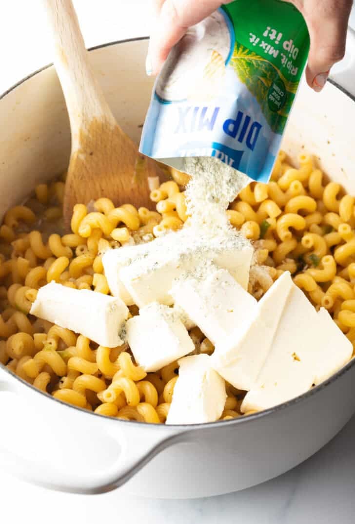 Large pieces of cheese and ranch dressing mix in a pot with pasta.