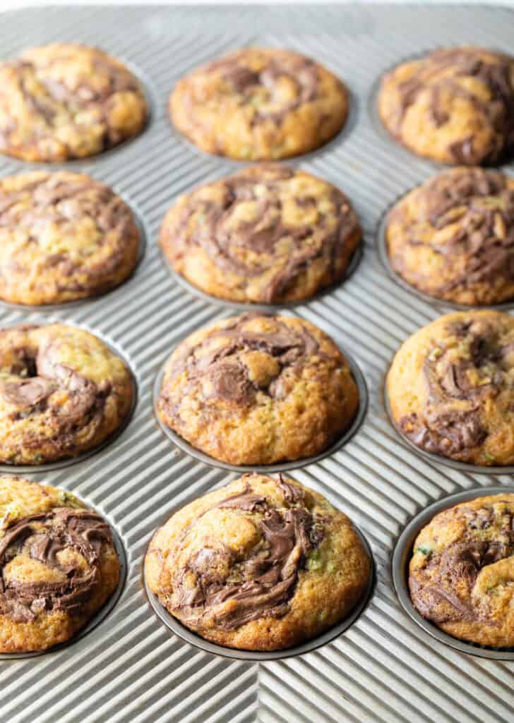A dozen zucchini and nutella muffins in a baking tin.