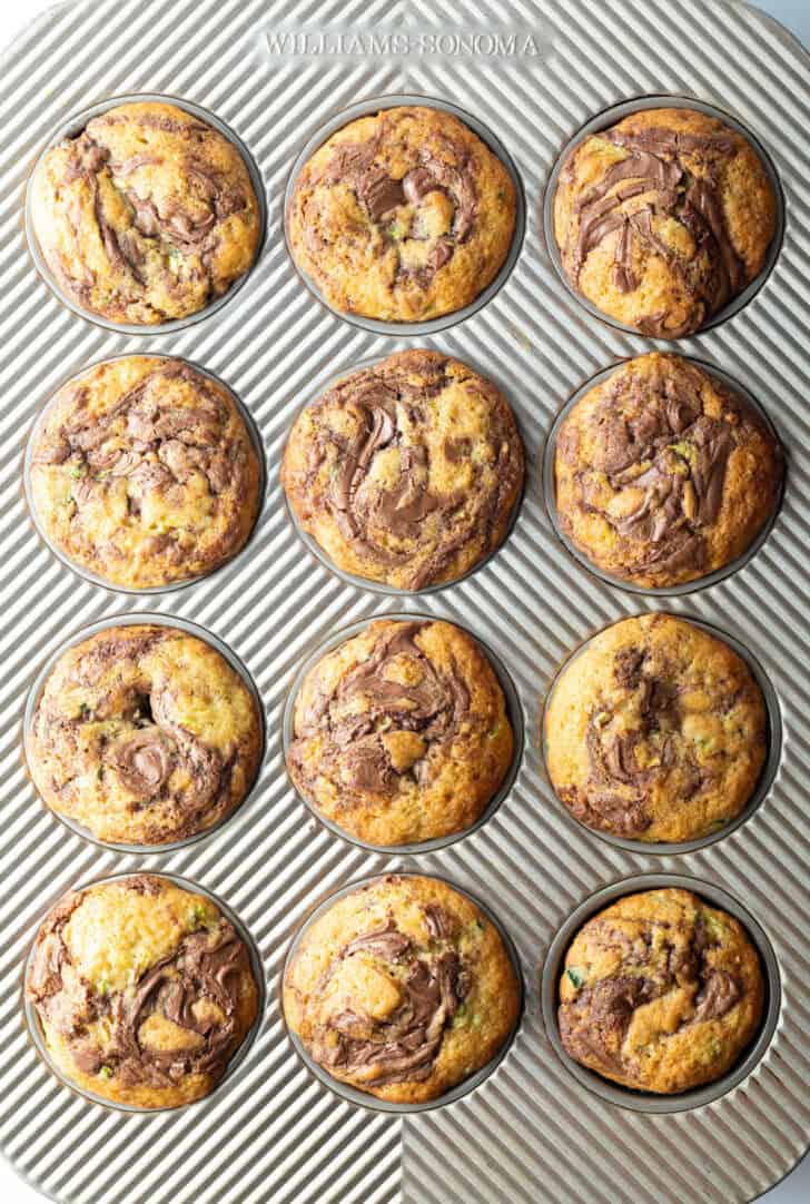 Top down view a dozen zucchini and nutella muffins in a baking tin.