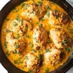 Top down view cast iron skillet packed with chicken thighs in a creamy Tuscan cream sauce.