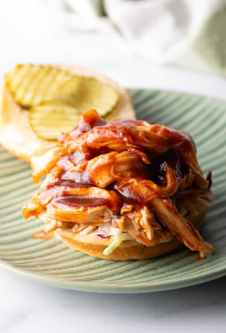 Open faced pulled barbecue chicken sandwich on a hamburger bun.