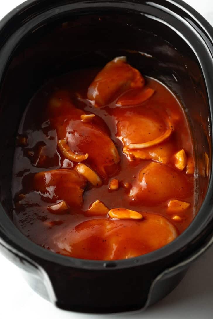 Crockpot with chicken thighs and barbecue sauce.