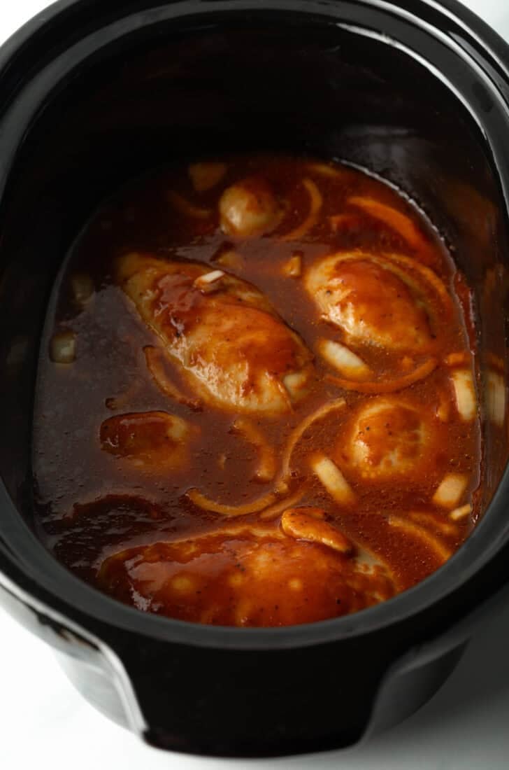 Crockpot with chicken thighs and barbecue sauce.