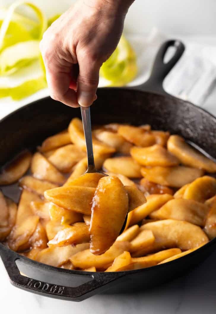 Spoon holding a serving of spiced apple slices to camera.