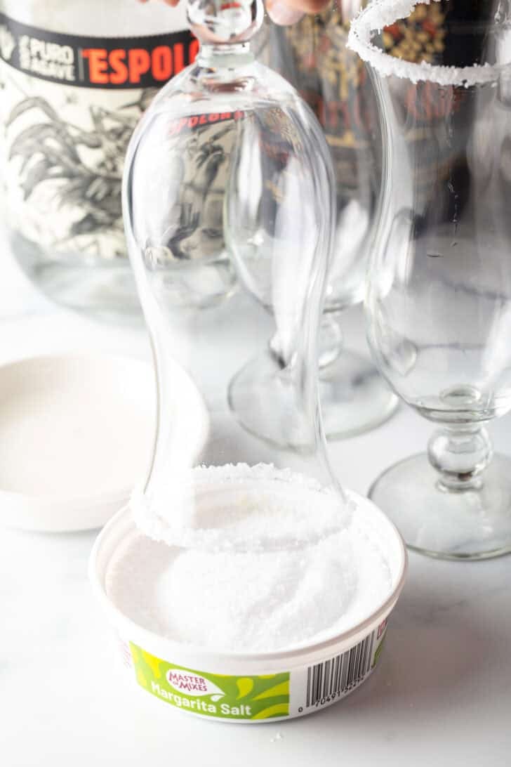 Dipping a the rim of a hurricane glass into a dish of salt.