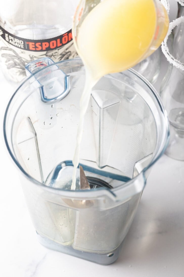 Pouring citrus juice into a blender jar.