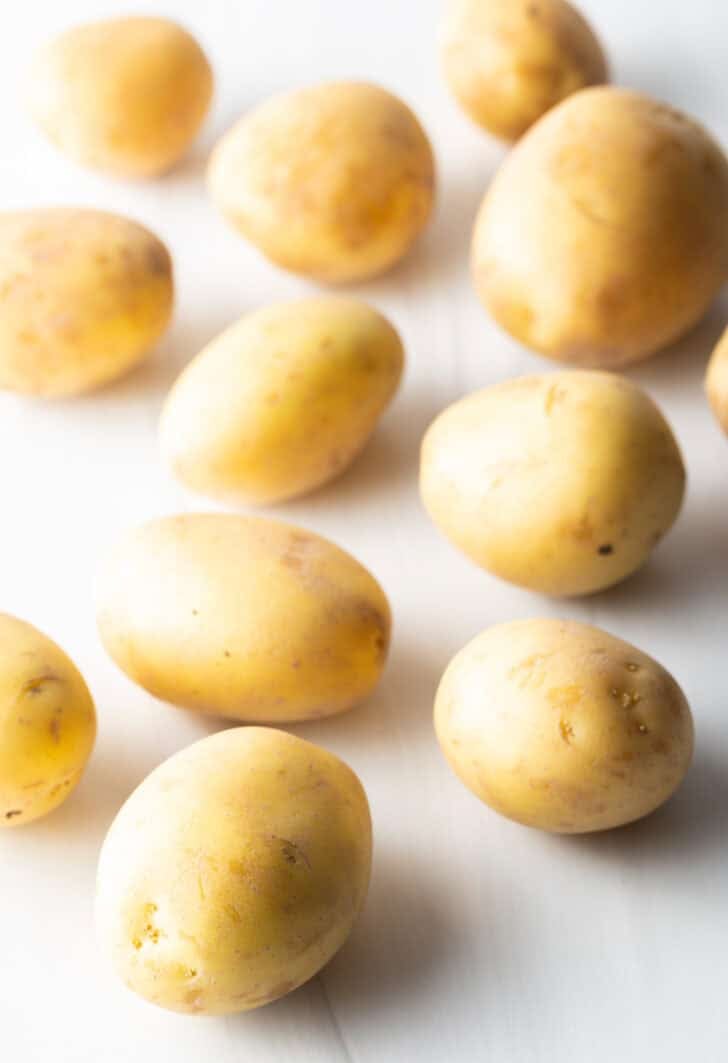 Several small yellow potatoes on a white background.