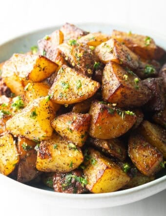 White bowl brimming with pieces of golden crispy Yukon potatoes.