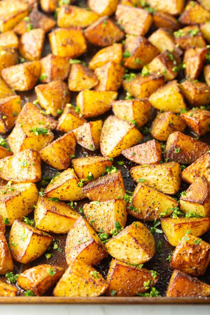 Top down view a rimmed baking sheet covered with chunks of crispy golden potatoes.