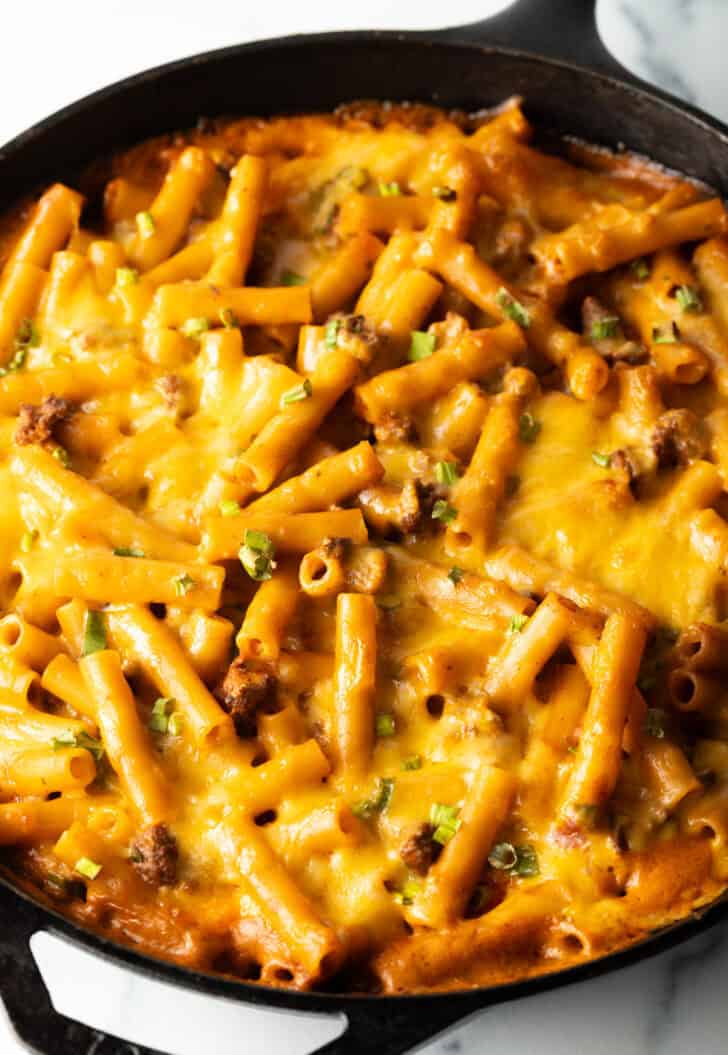 Deep black cast iron skillet with long noodles, ground beef, and cheese.