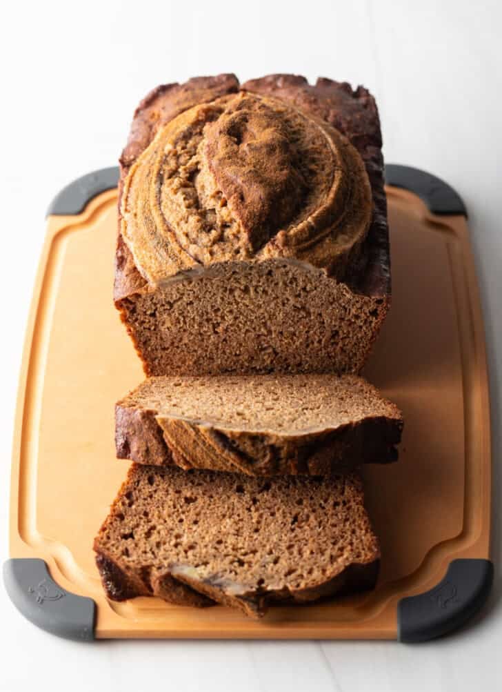 Loaf of healthy banana bread on a cutting board. Two front slices are layered.