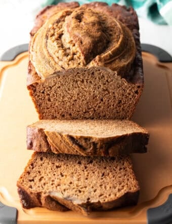 Loaf of healthy banana bread on a cutting board. Two front slices are layered.