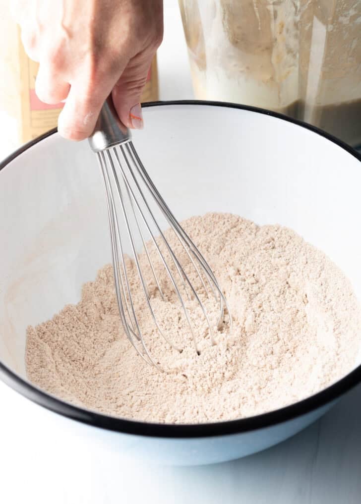 Whisking dry ingredients in a white mixing bowl.