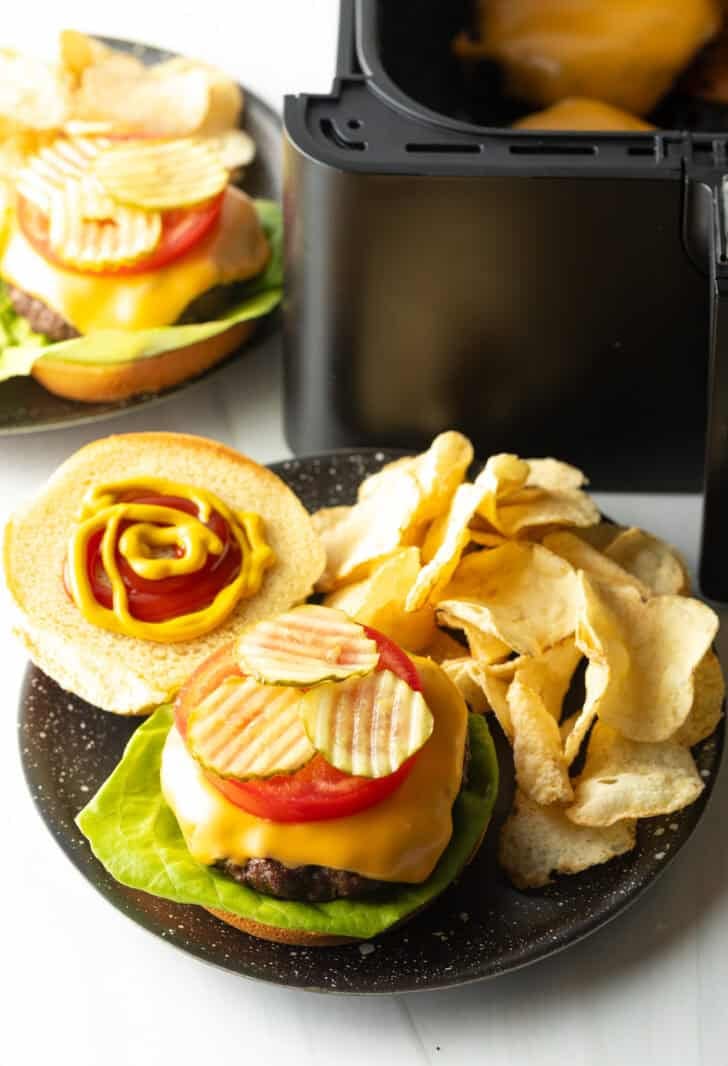 Top down view open faced cheeseburger on a plate with potato chips.