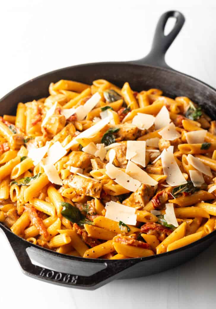 Cast iron skillet with pasta, chicken, and sun dried tomato sauce.