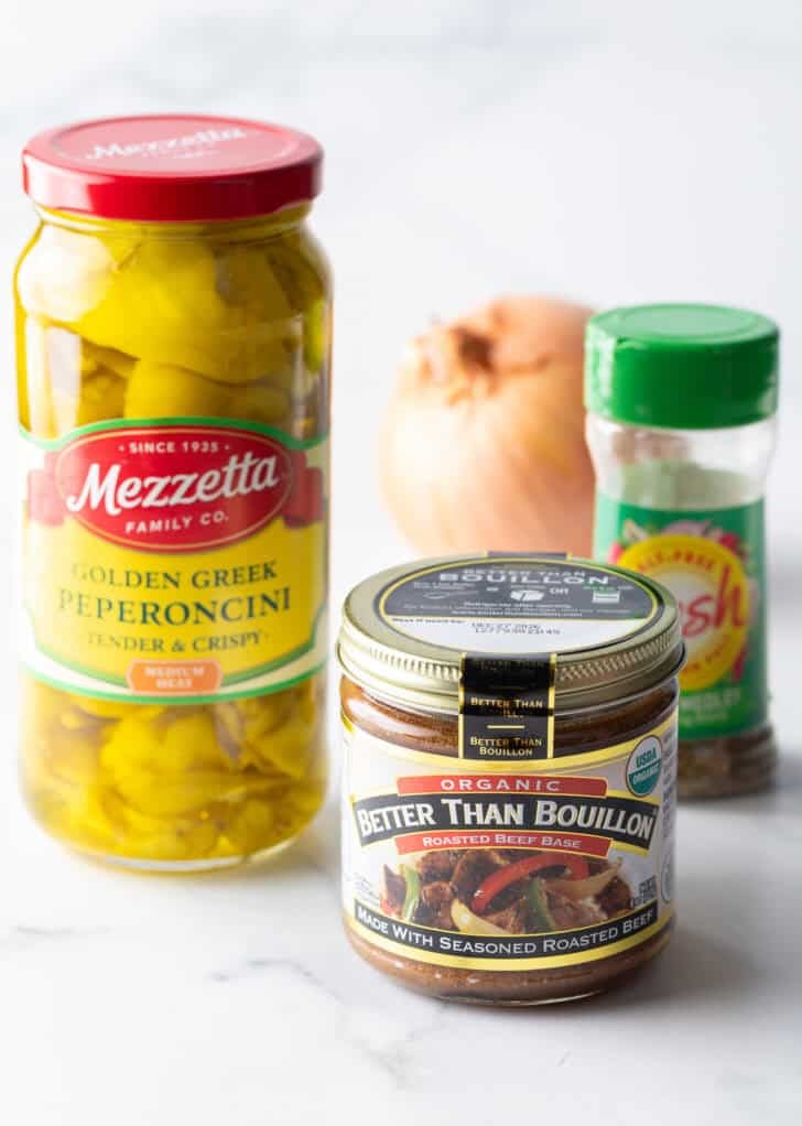 Recipe ingredients: Jar of beef bullion, jar of pickled pepperonicini, Italian seasoning, and whole onion.
