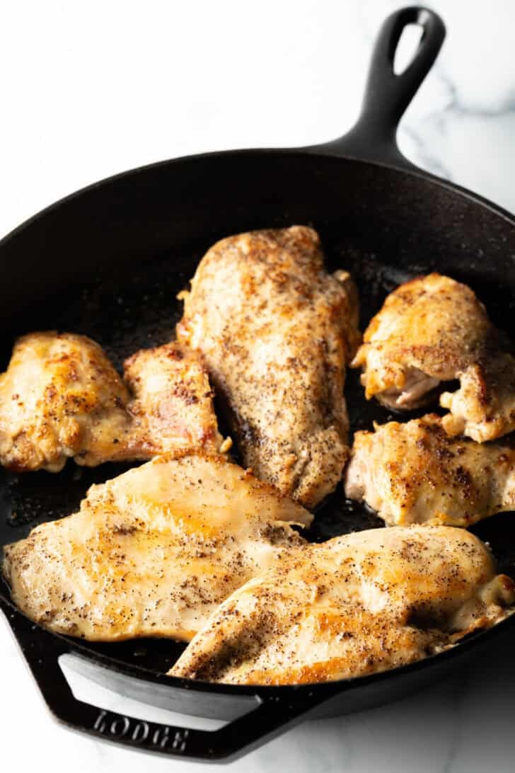 4 seared chicken breast cutlets in a cast iron skillet.