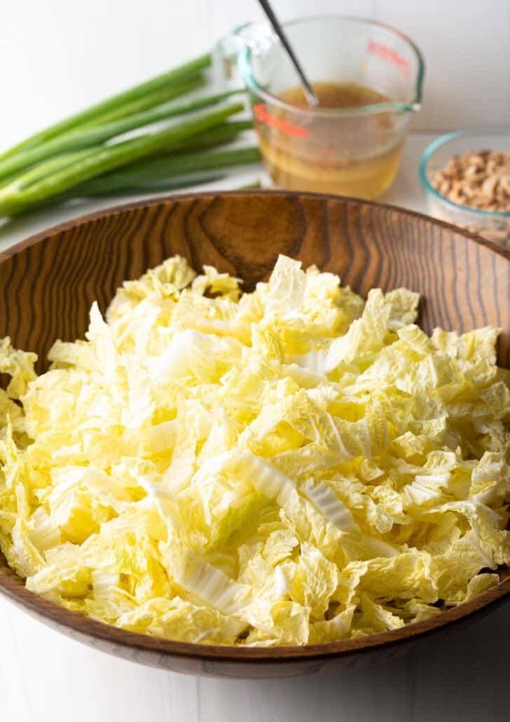 Shredded napa cabbage in a wood bowl.
