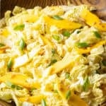 Wood bowl with green napa cabbage, mango slices, and green onions.