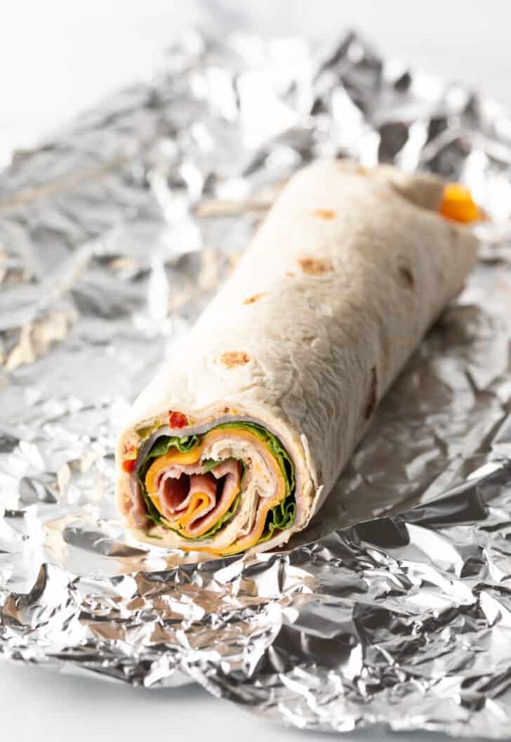 Tortilla wrapped with ham, cheese, spinach, and cream cheese.
