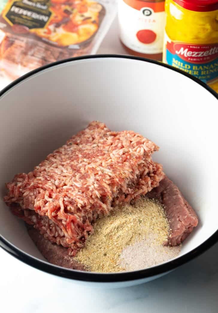 White bowl with grouind beef, breadcrumbs, and seasoning.