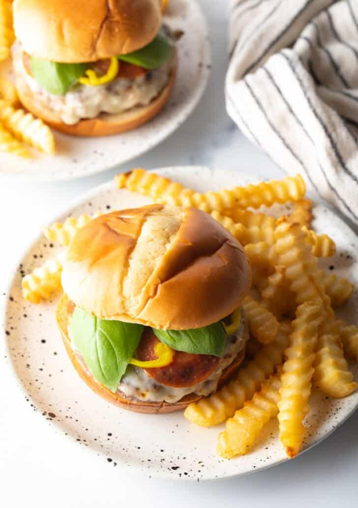 Pizza burger on plate, with french fries.