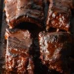 4 sections of cooked baby back ribs on a baking sheet.