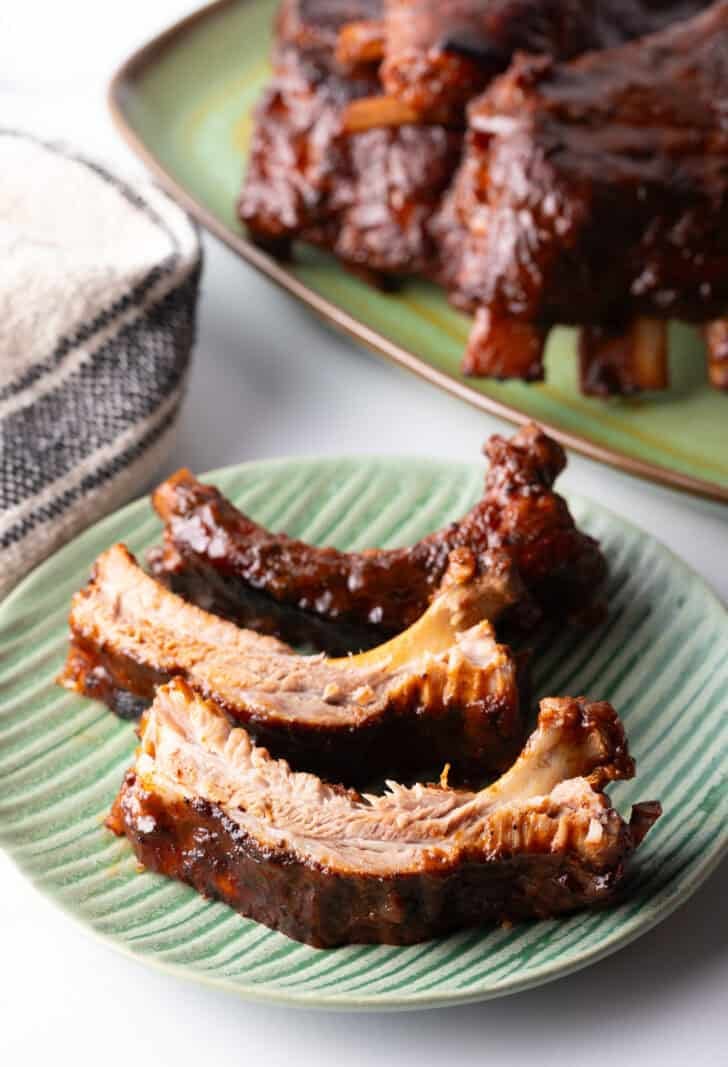 3 saucy ribs on a green plate.