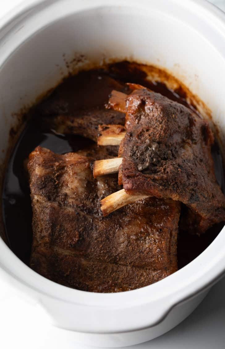 4 sections of ribs cooked in a slow cooker.