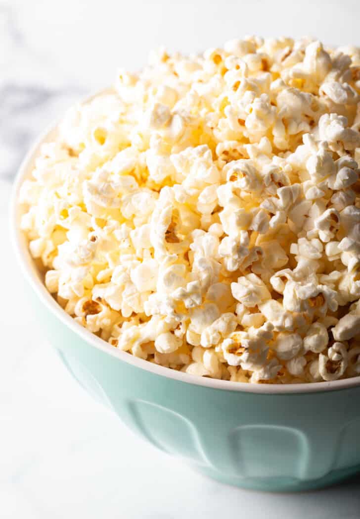Blue bowl overflowing with butter popcorn.