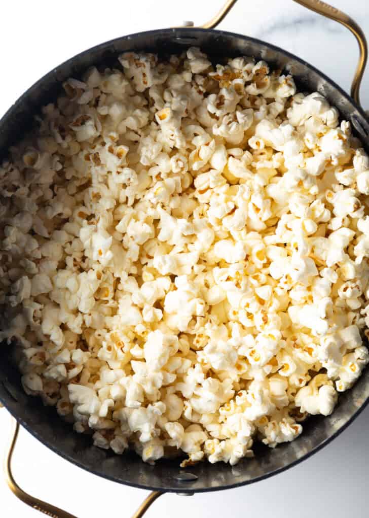 Cooking popcorn on the stovetop in a large black pot.