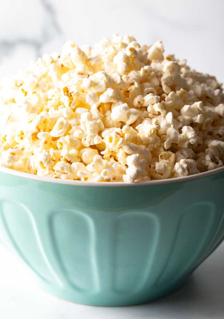 Blue bowl overflowing with butter popcorn.