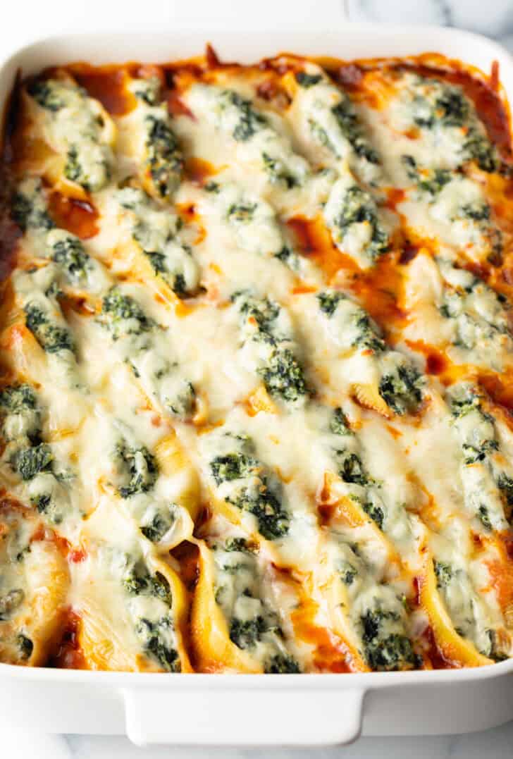 Top down view large rectangle baking dish with spinach and meat stuffed shells.