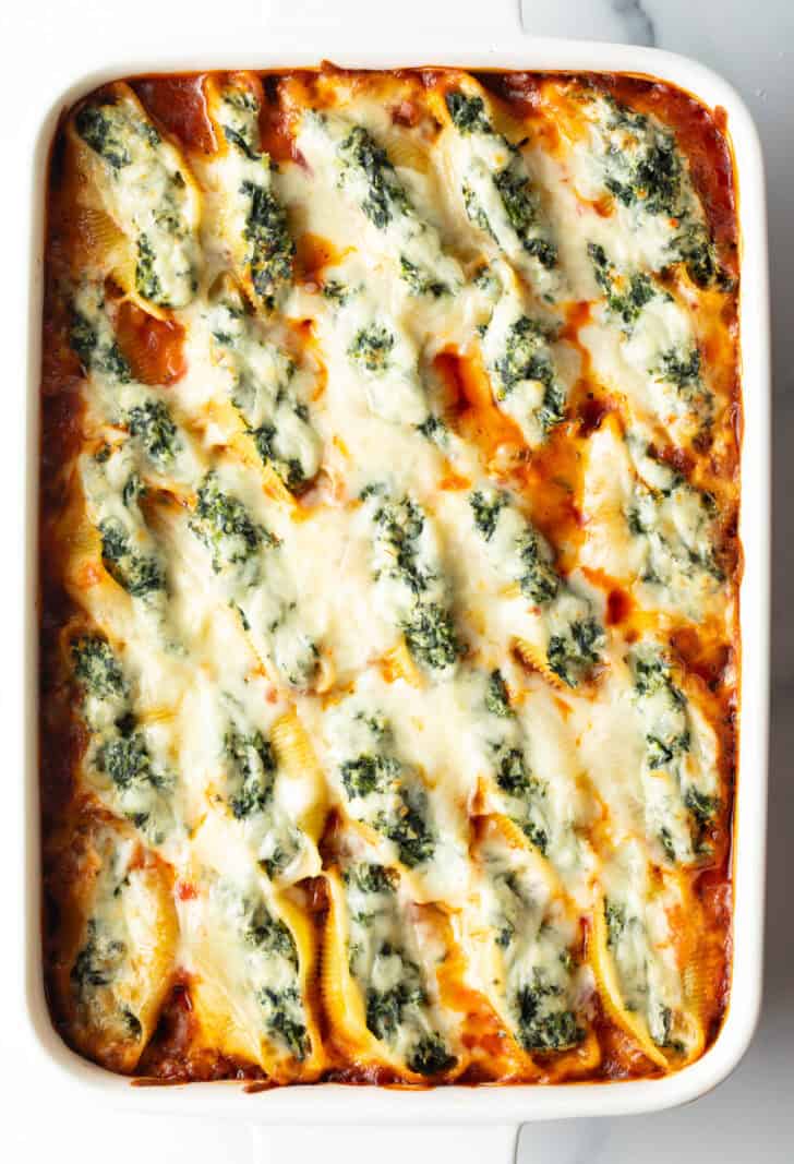 Top down view large rectangle baking dish with spinach and meat stuffed shells.