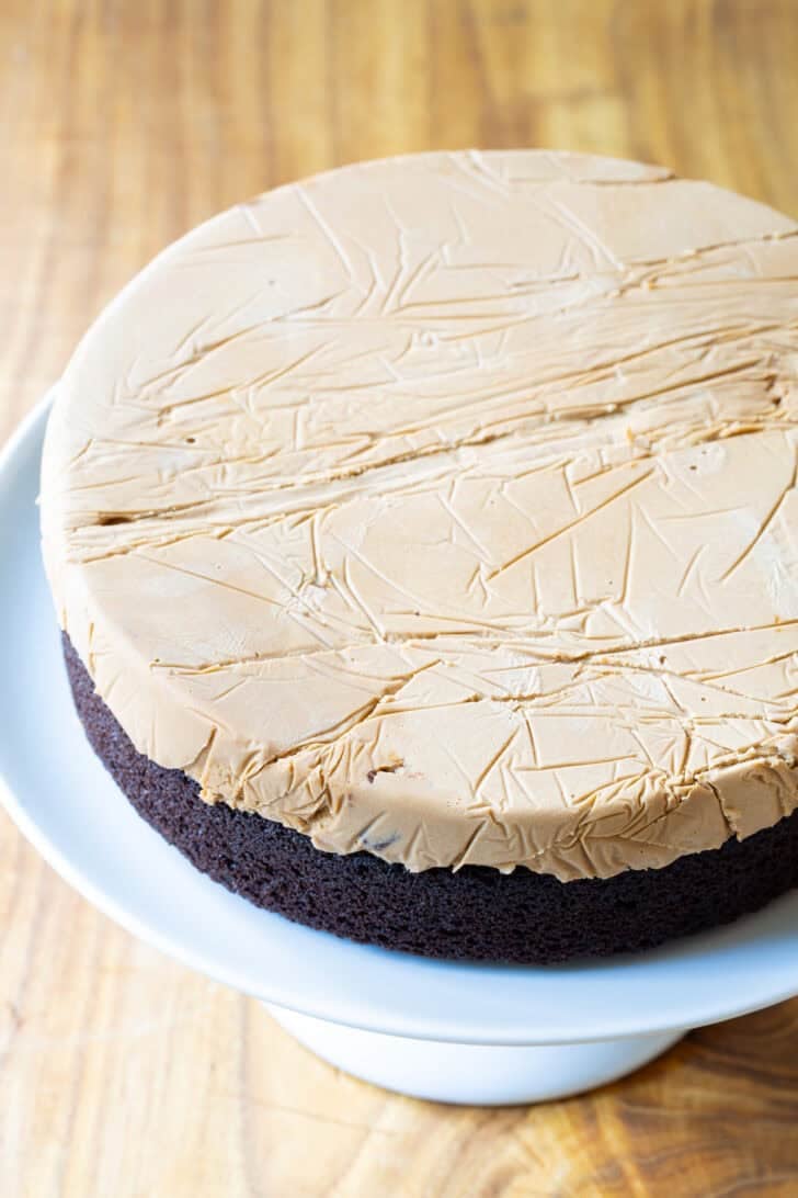 Disc of caramel ice cream layered on top of round chocolate cake base.