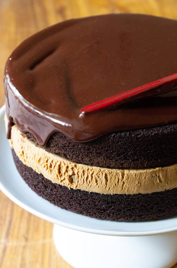 Covering chocolate and caramel ice cream cake with dripping chocolate ganache.