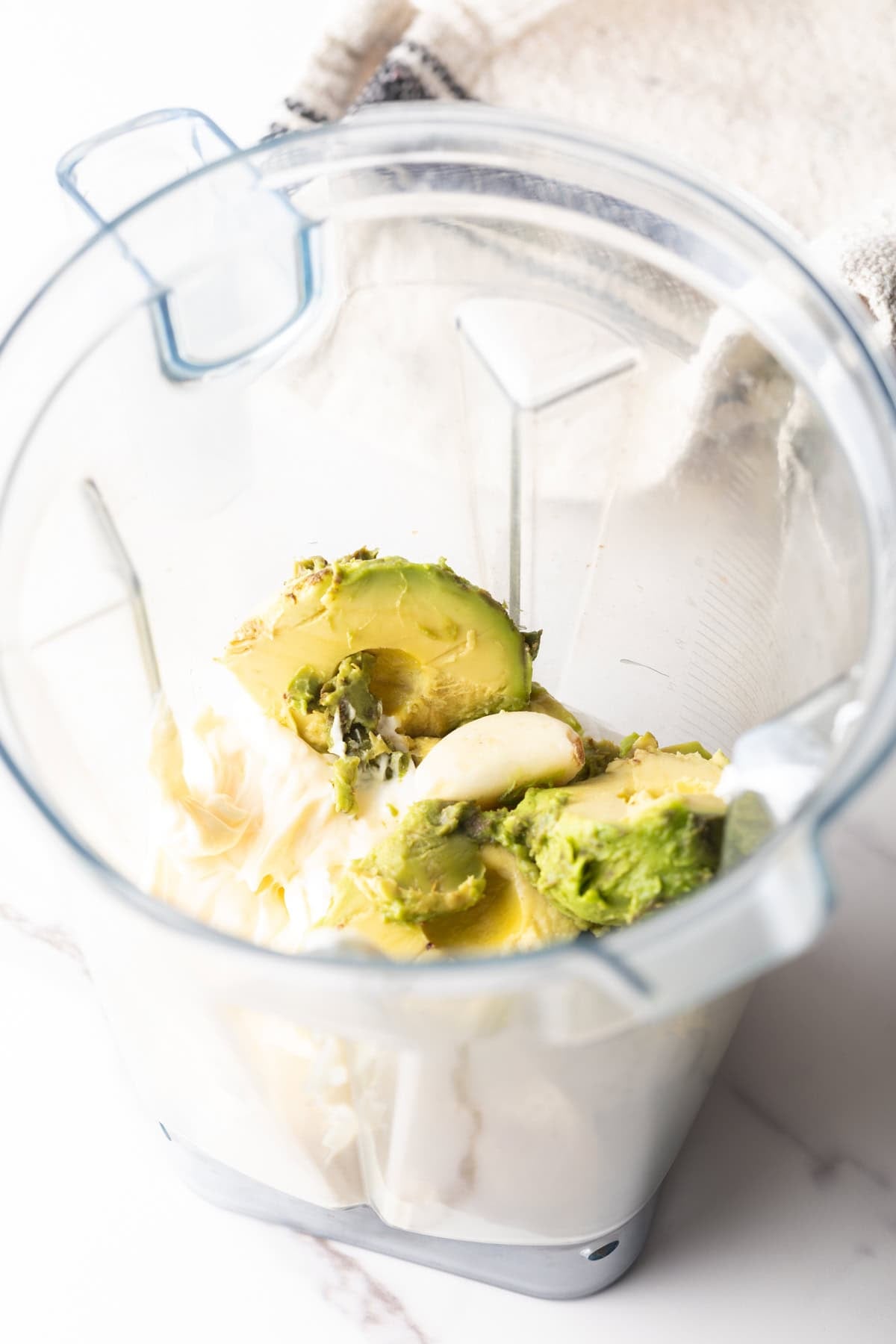 Mayonnaise, avocado slices, and lime juice sitting in a blender.