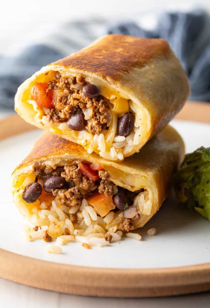Two halves of a beef and cheese burrito stacked on top of each other.