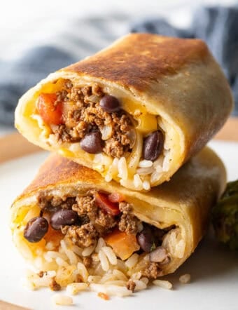 Two halves of a beef and cheese burrito stacked on top of each other.